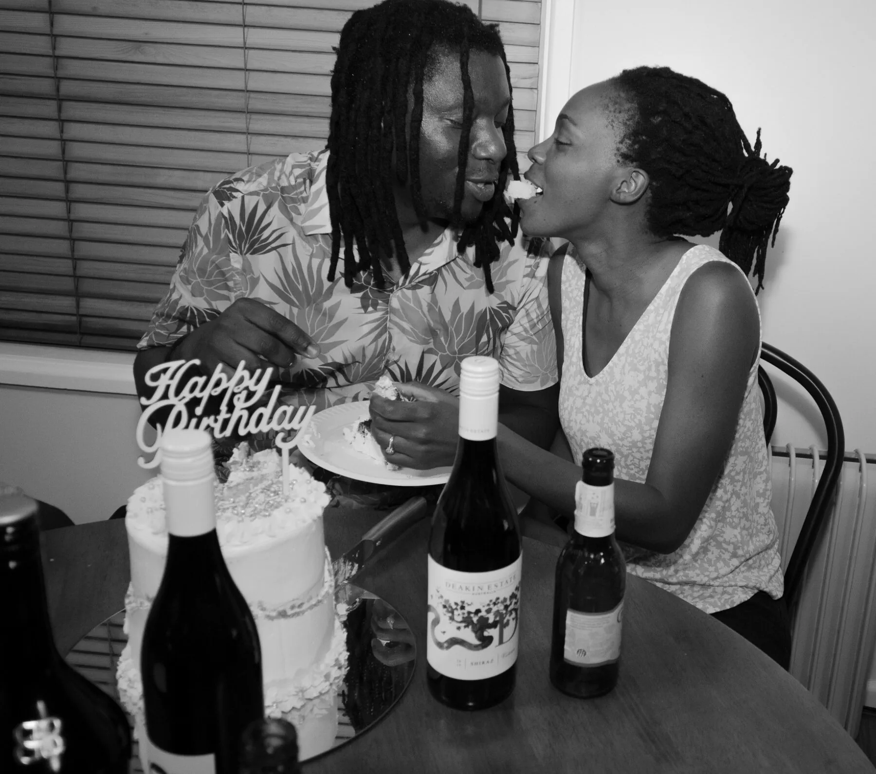 A couple sharing birthday cake in a black-and-white candid photograph