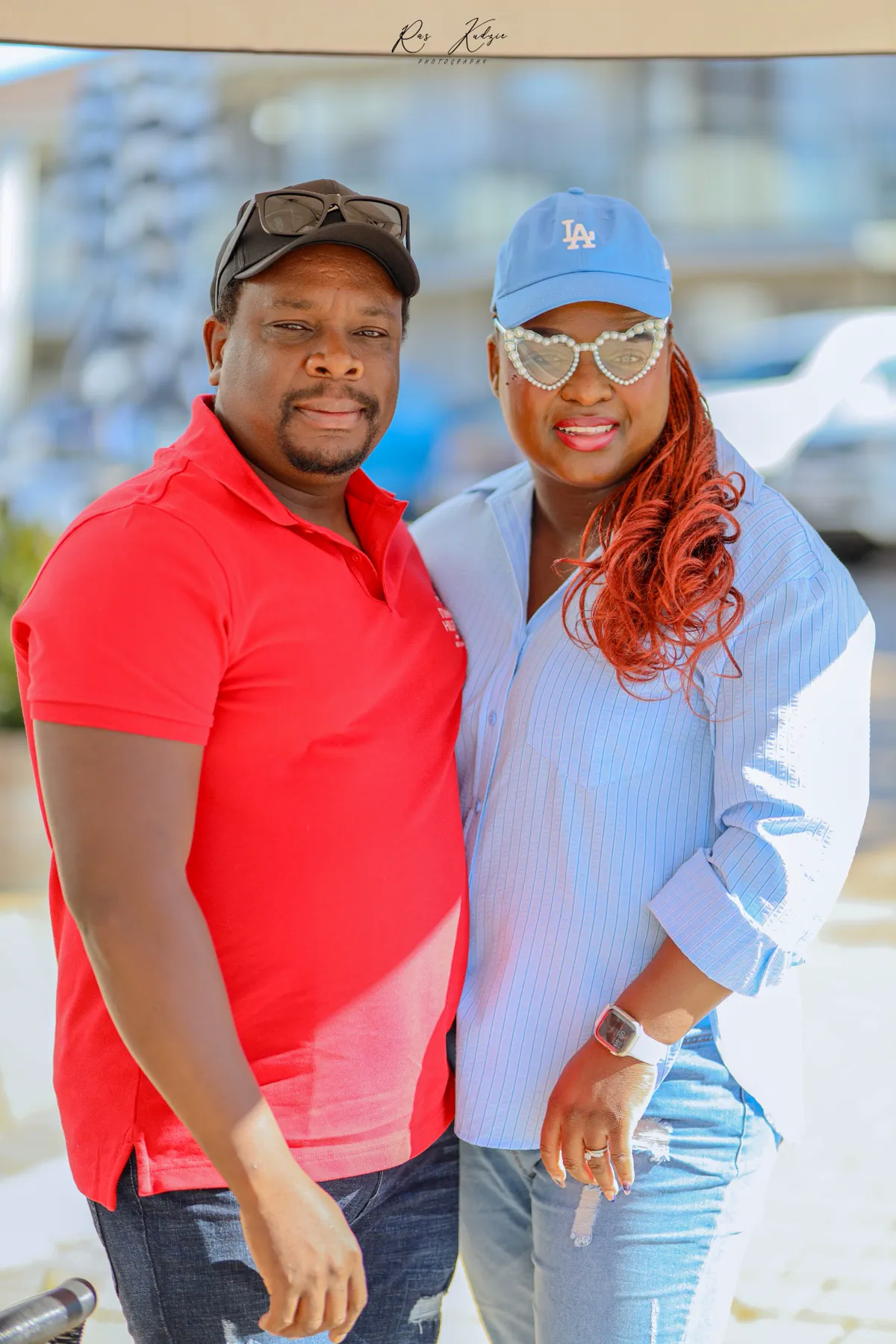 A couple posing together in coordinated red and blue caps