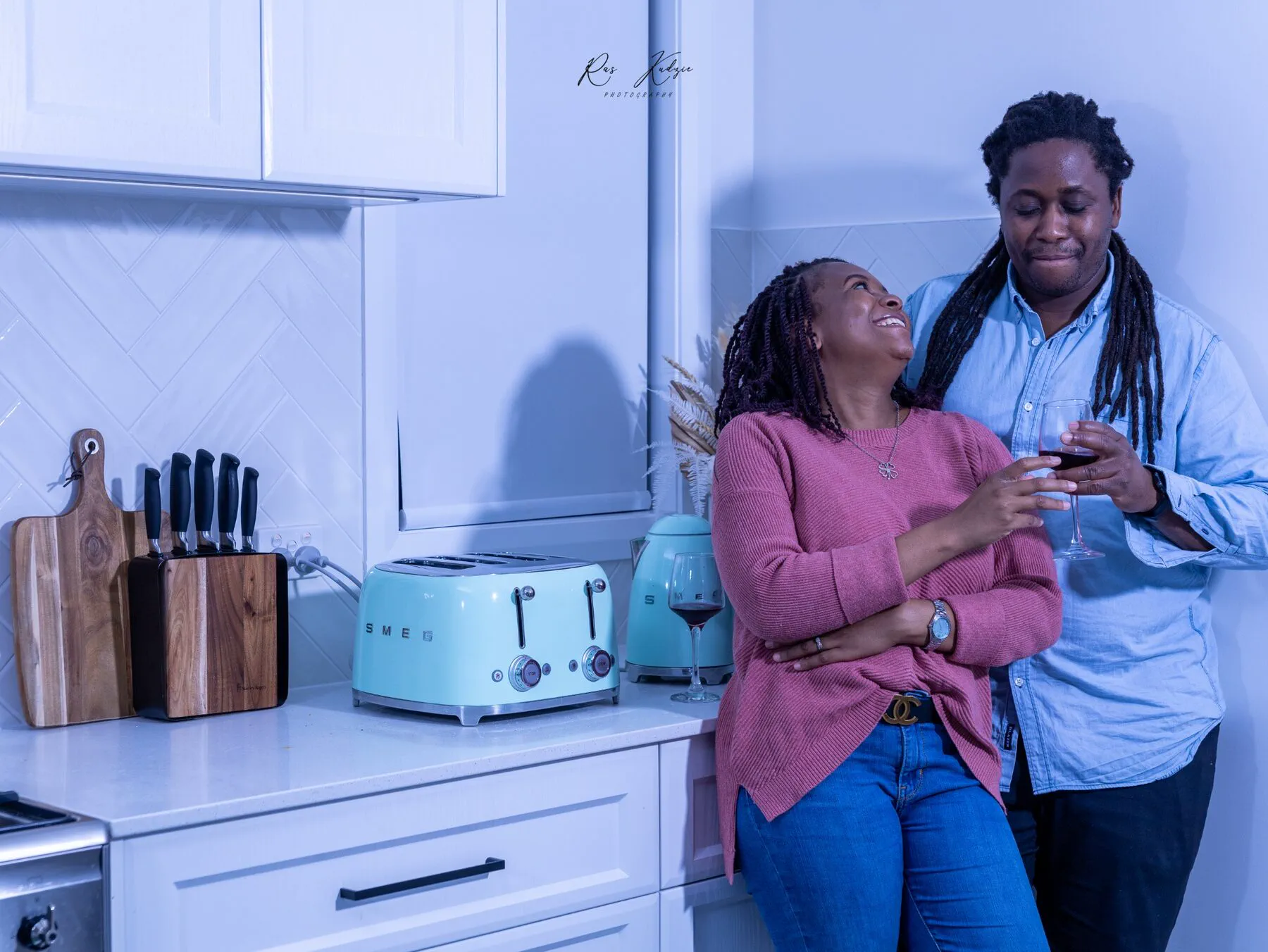 A couple sharing wine and an affectionate look in their kitchen