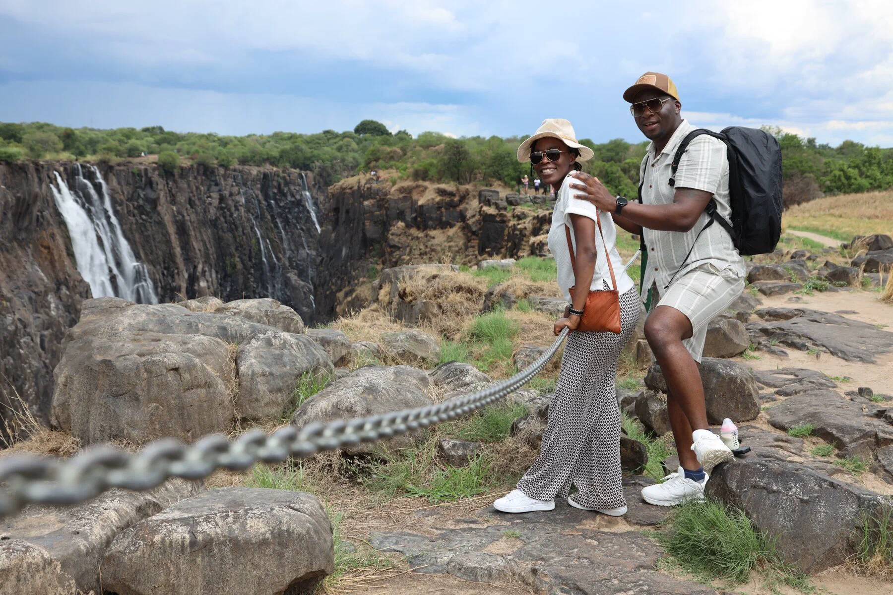 A smiling couple exploring together beside Victoria Falls