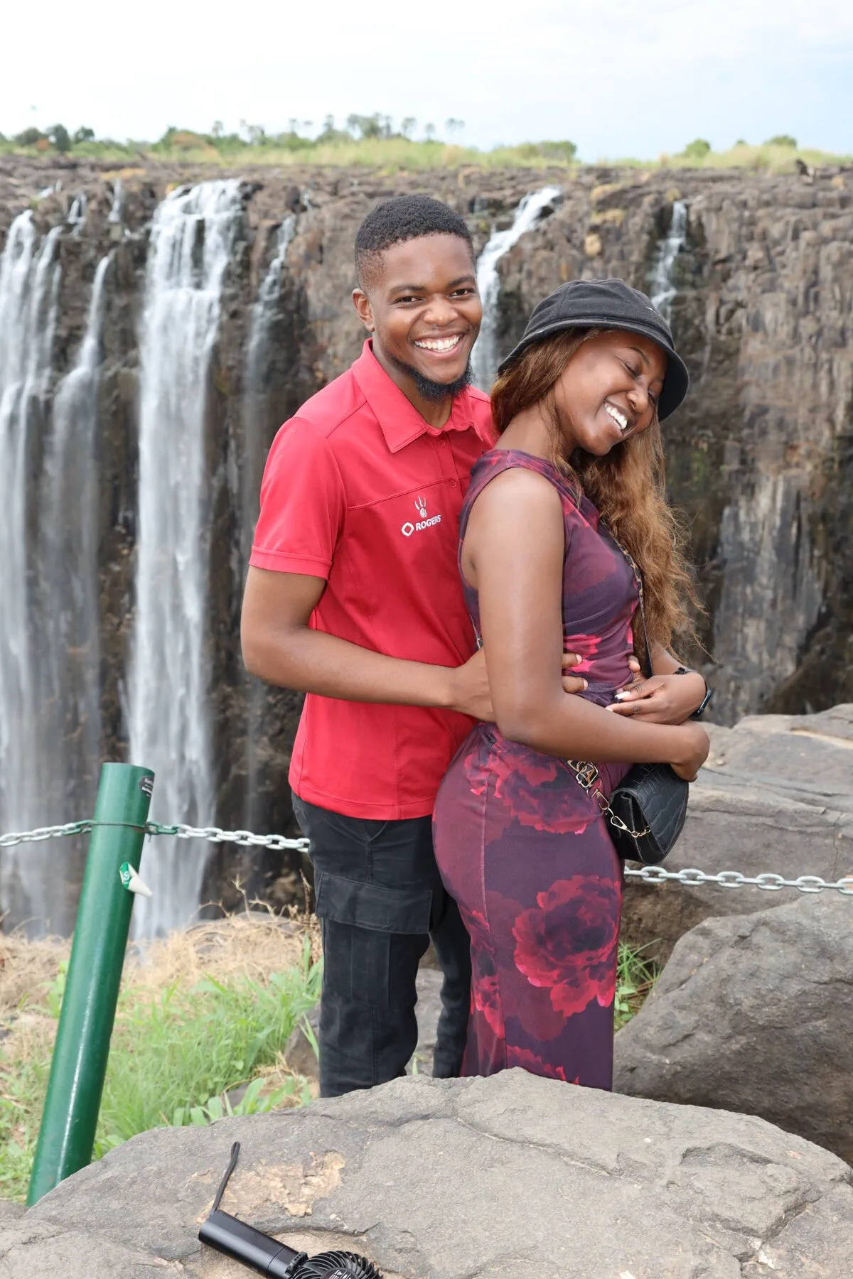 A young couple embracing in front of Victoria Falls