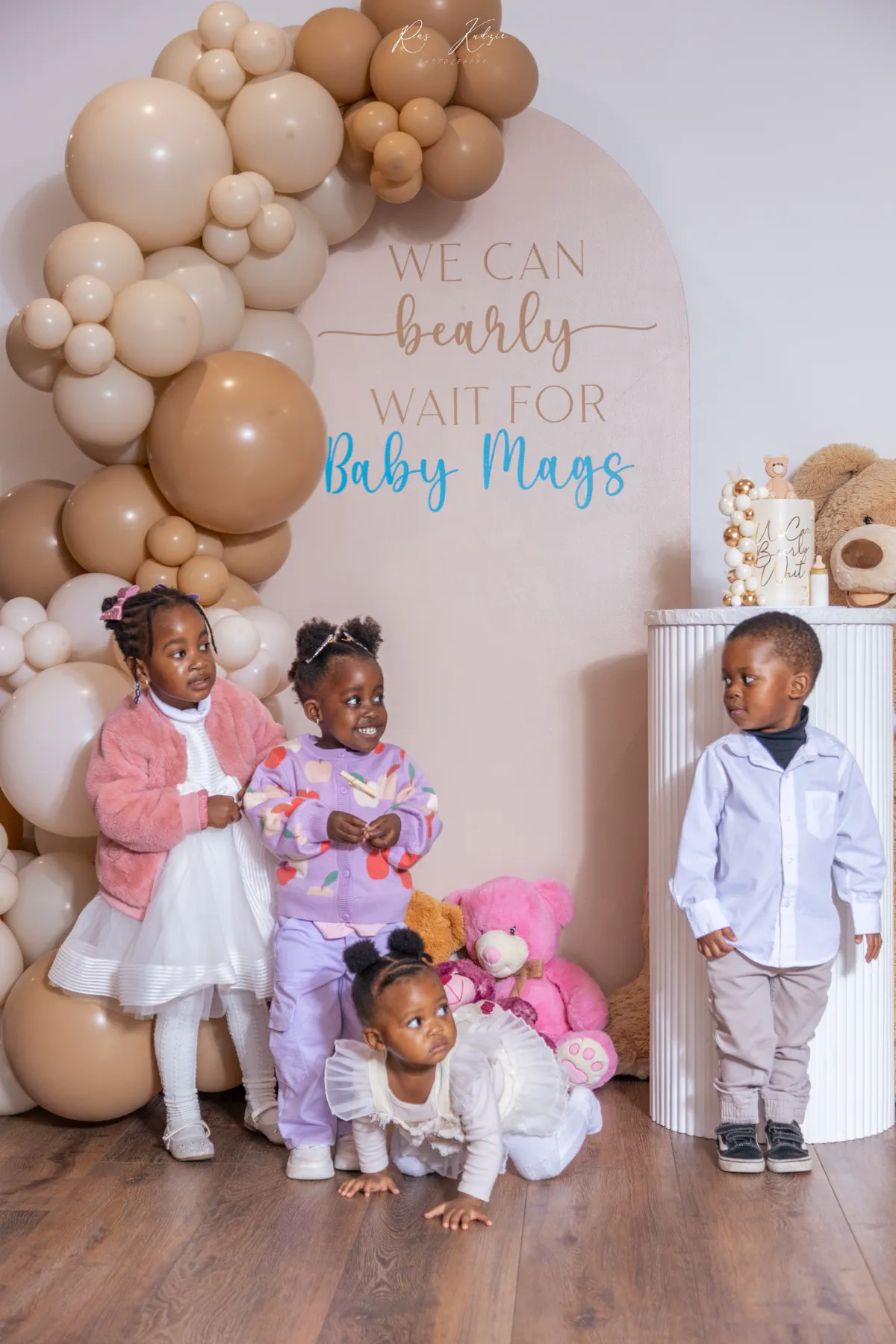 Children gathered beneath a balloon arch at a baby shower