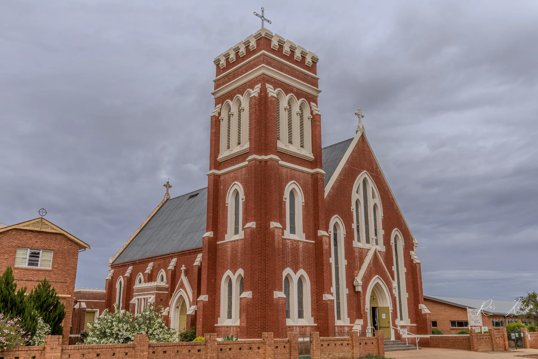 A red-brick country church beneath a dramatic grey sky