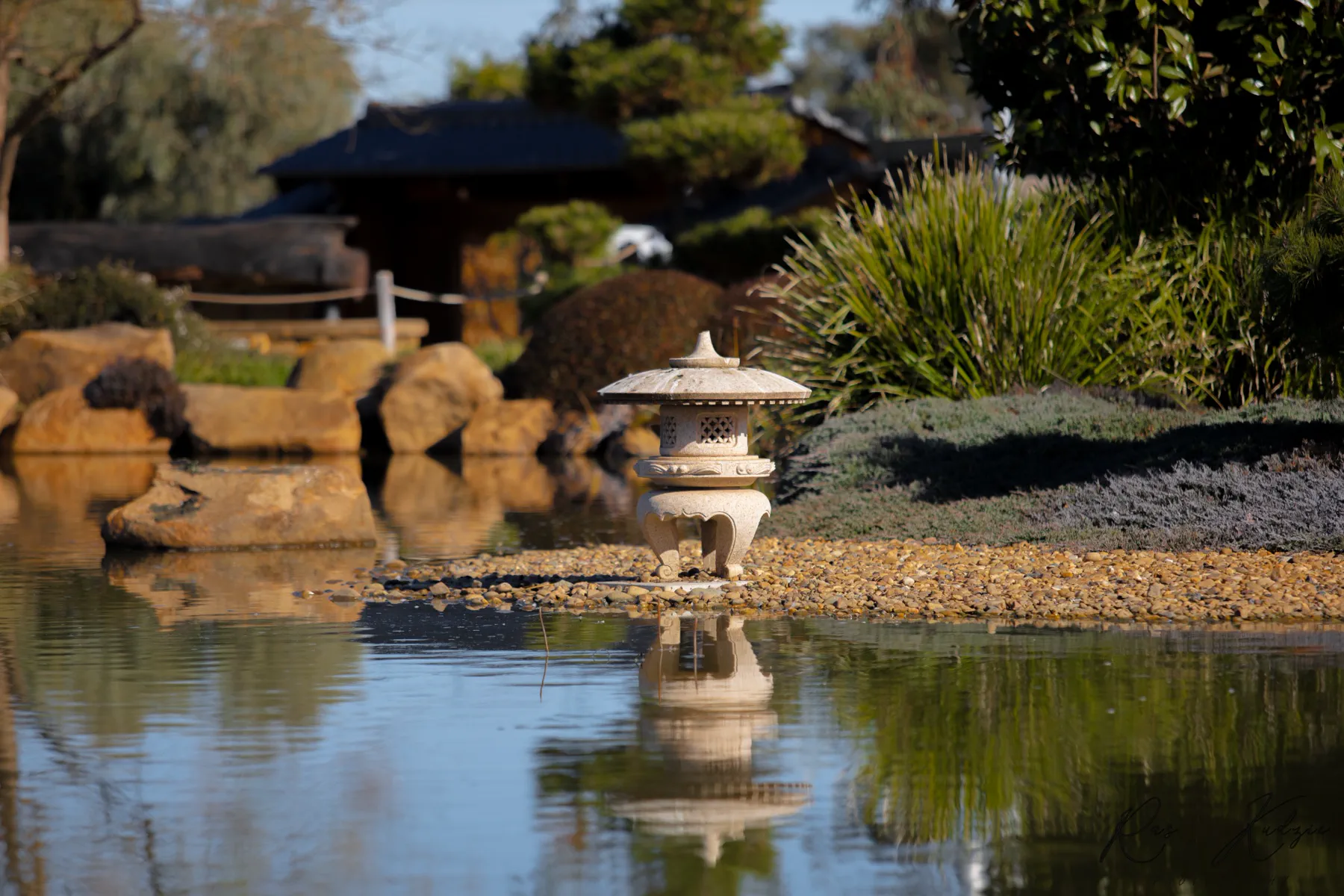 A stone lantern reflected in the still water of a Japanese garden