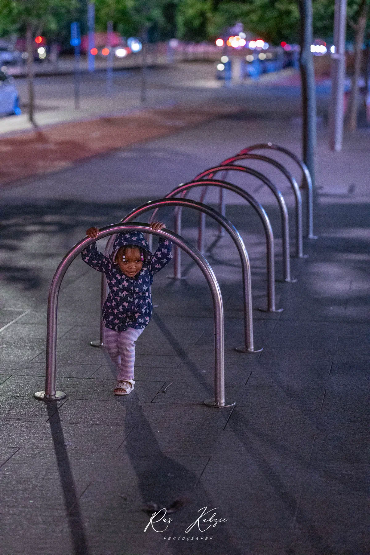 A young child framed by repeating metal arches beneath city lights