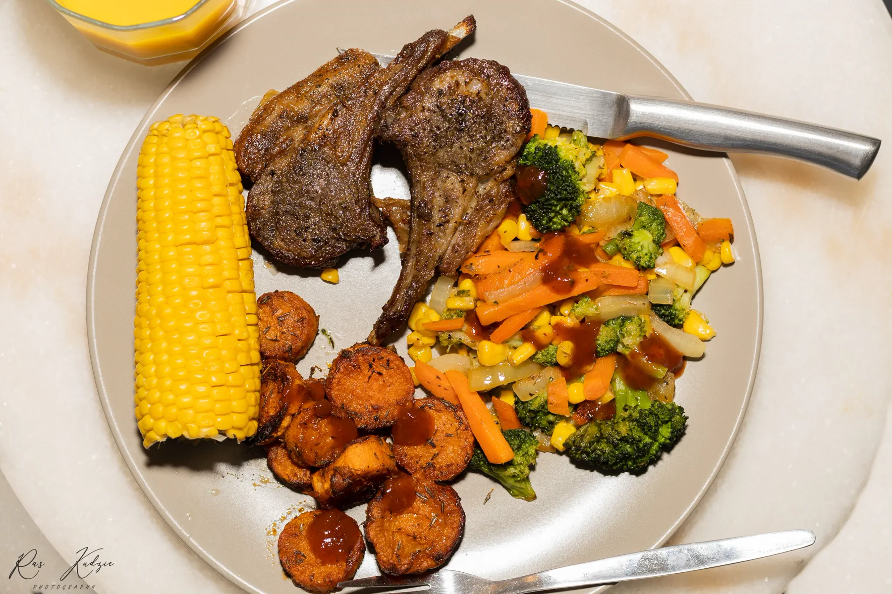 Close still life of grilled lamb, corn, sweet potato and vegetables