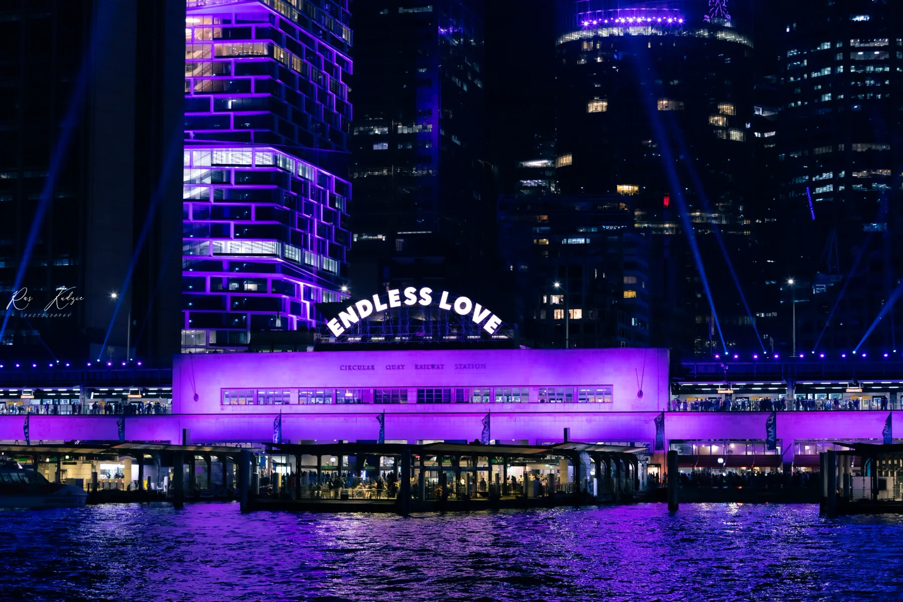 Circular Quay glowing in violet light beneath an Endless Love installation at night