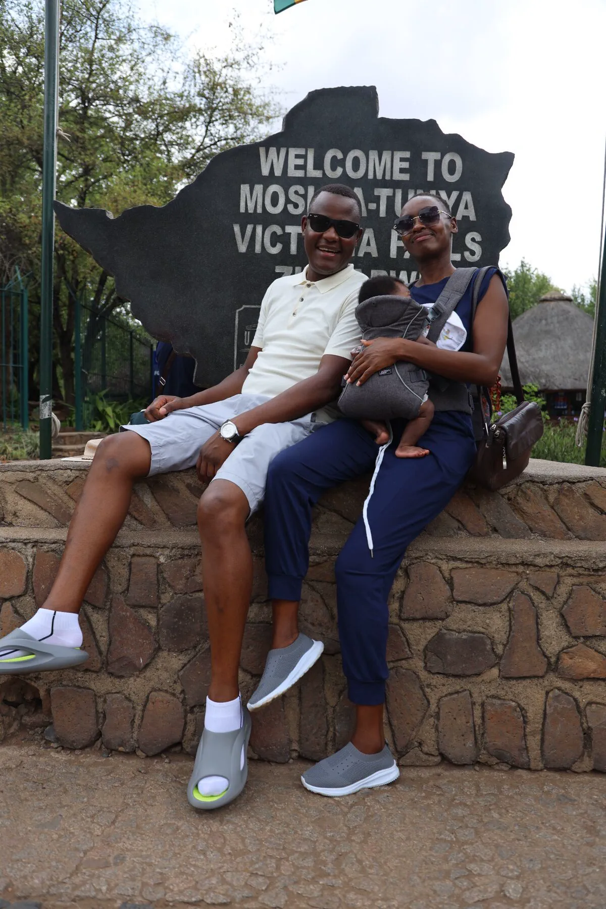 A family with their baby smiling together at Victoria Falls