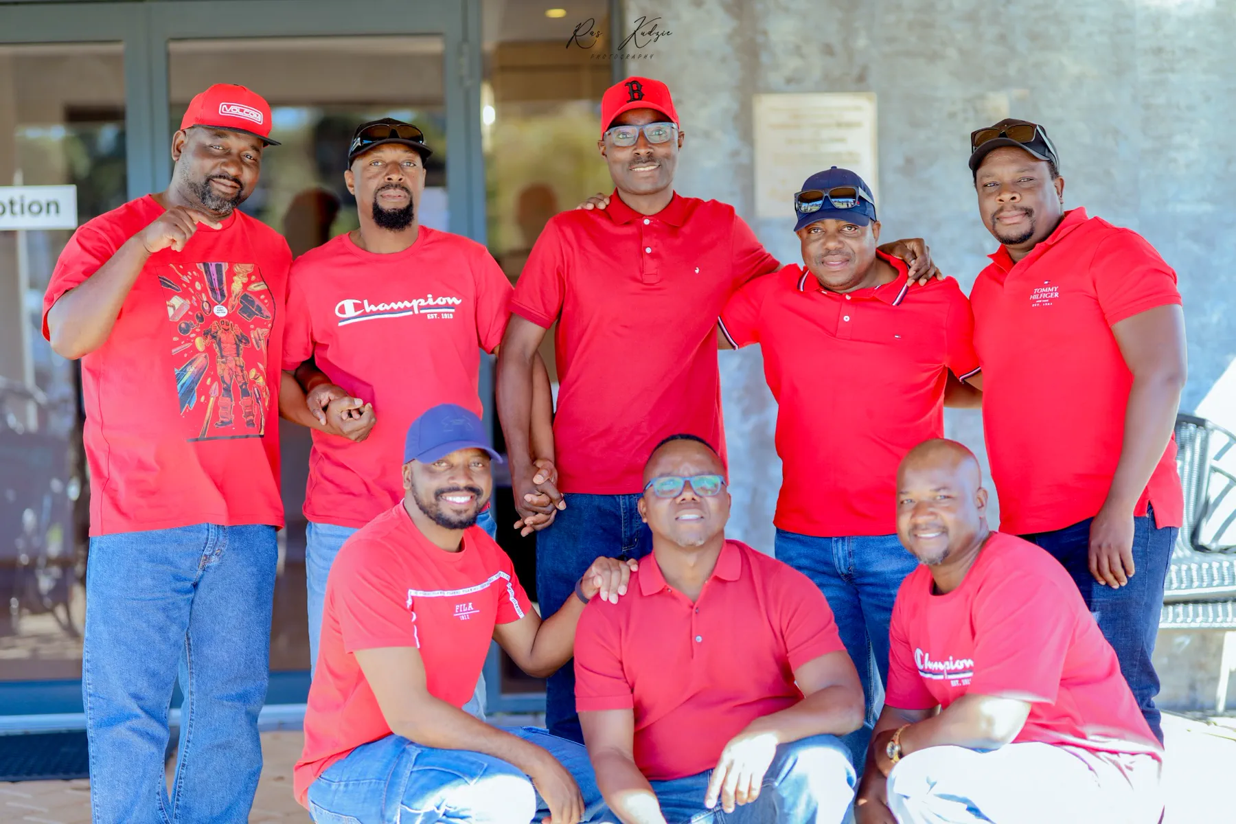 A group of men posing together in coordinated red shirts