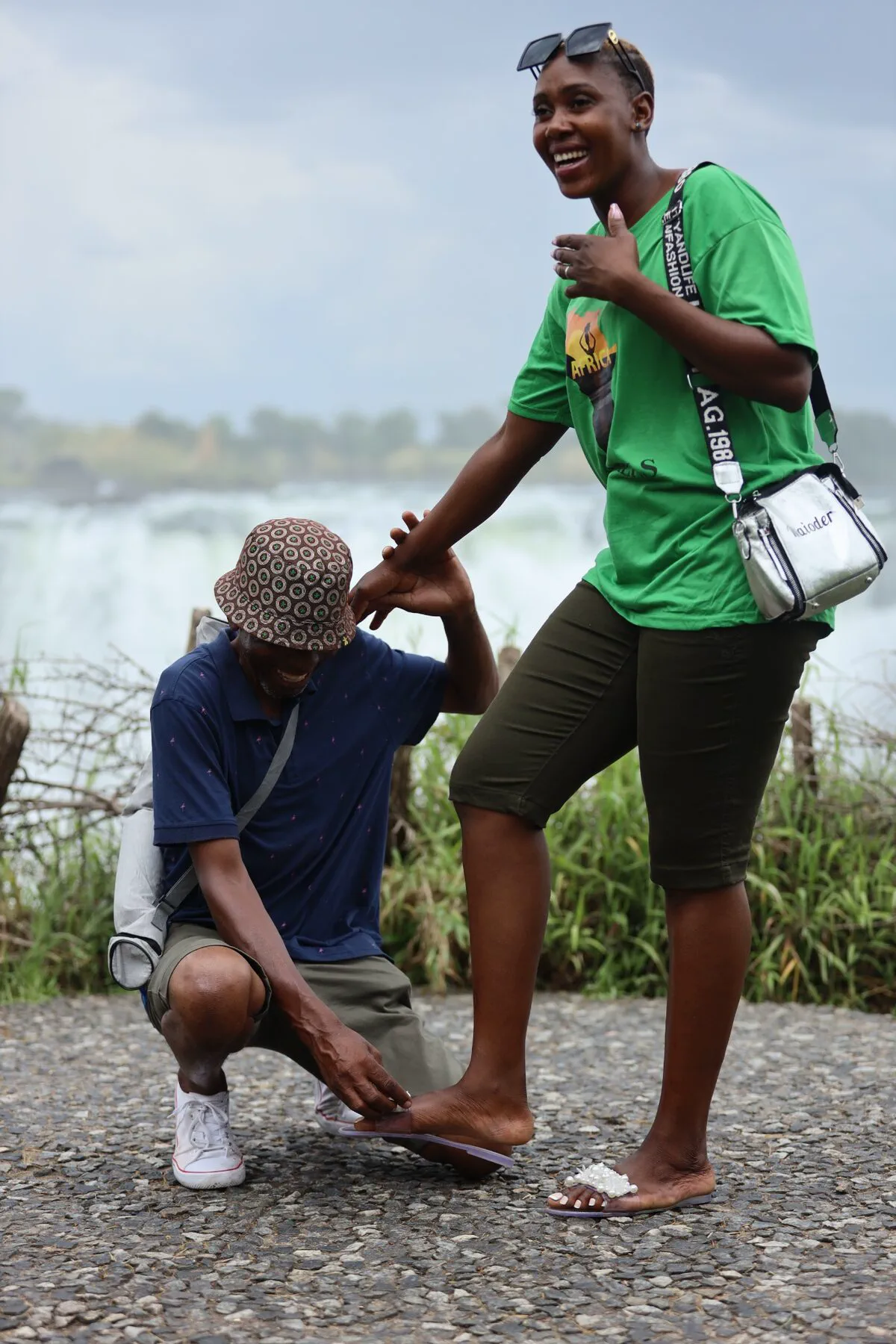 A playful candid moment between two travellers beside the falls
