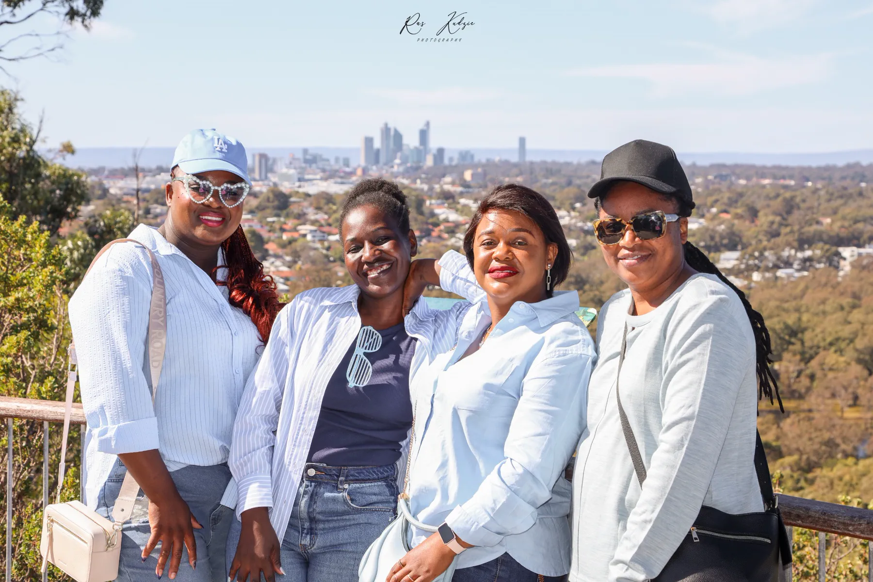Four women posing together with the Perth skyline behind them