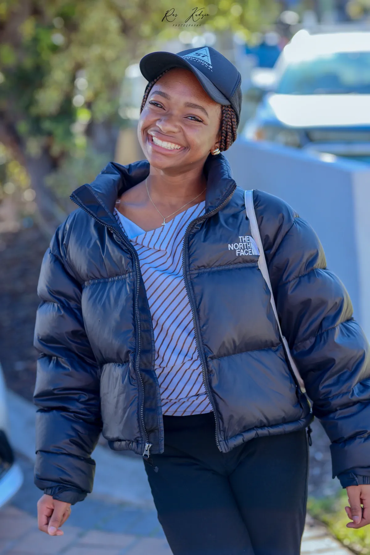 A smiling young woman in a navy jacket and cap