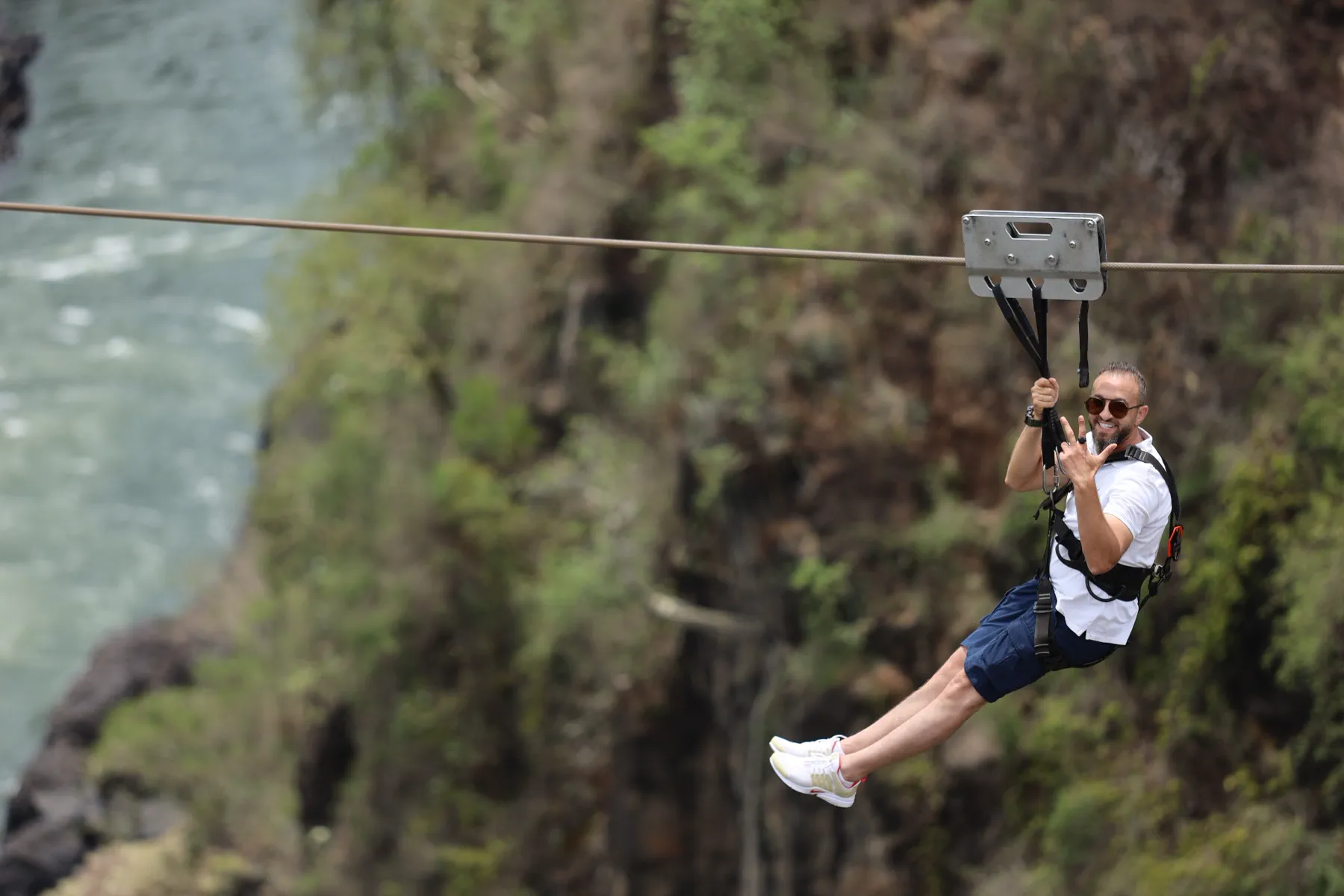 A smiling traveller crossing a gorge by zipline